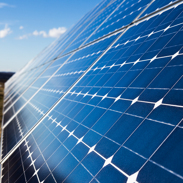 Angled close-up view of dark blue solar panels set against a clear blue sky.